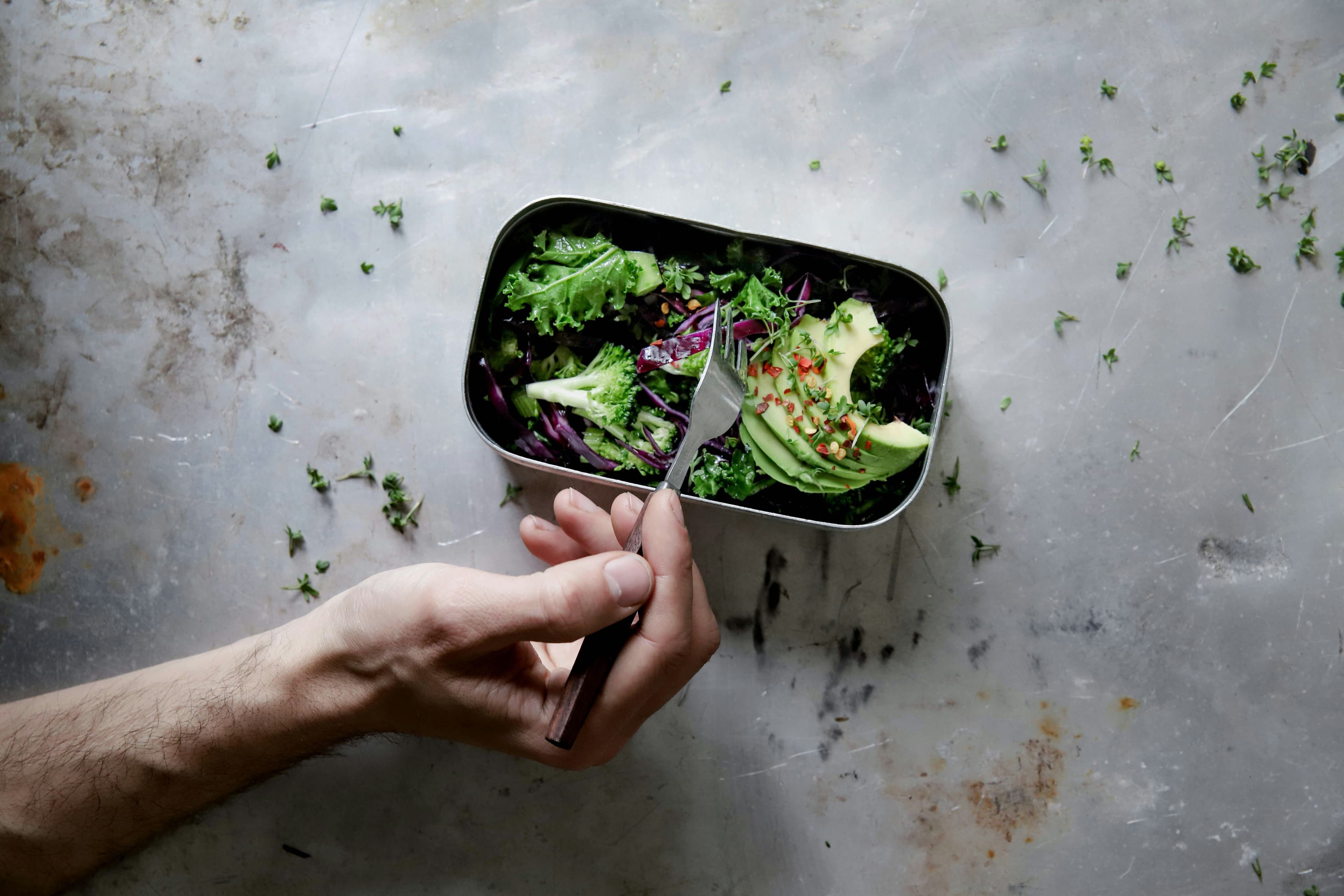 Hand with fork in metal lunchbox