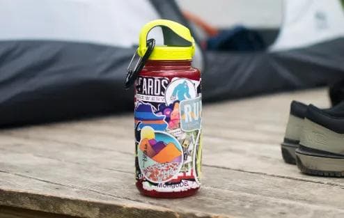 red nalgene water bottle with stickers on table